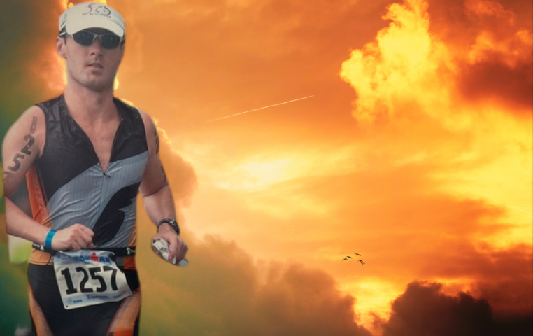 Endurance athlete Lukas Temer running in a race, wearing a triathlon suit with bib number 1257, against a backdrop of a vibrant orange sunset with dramatic clouds.